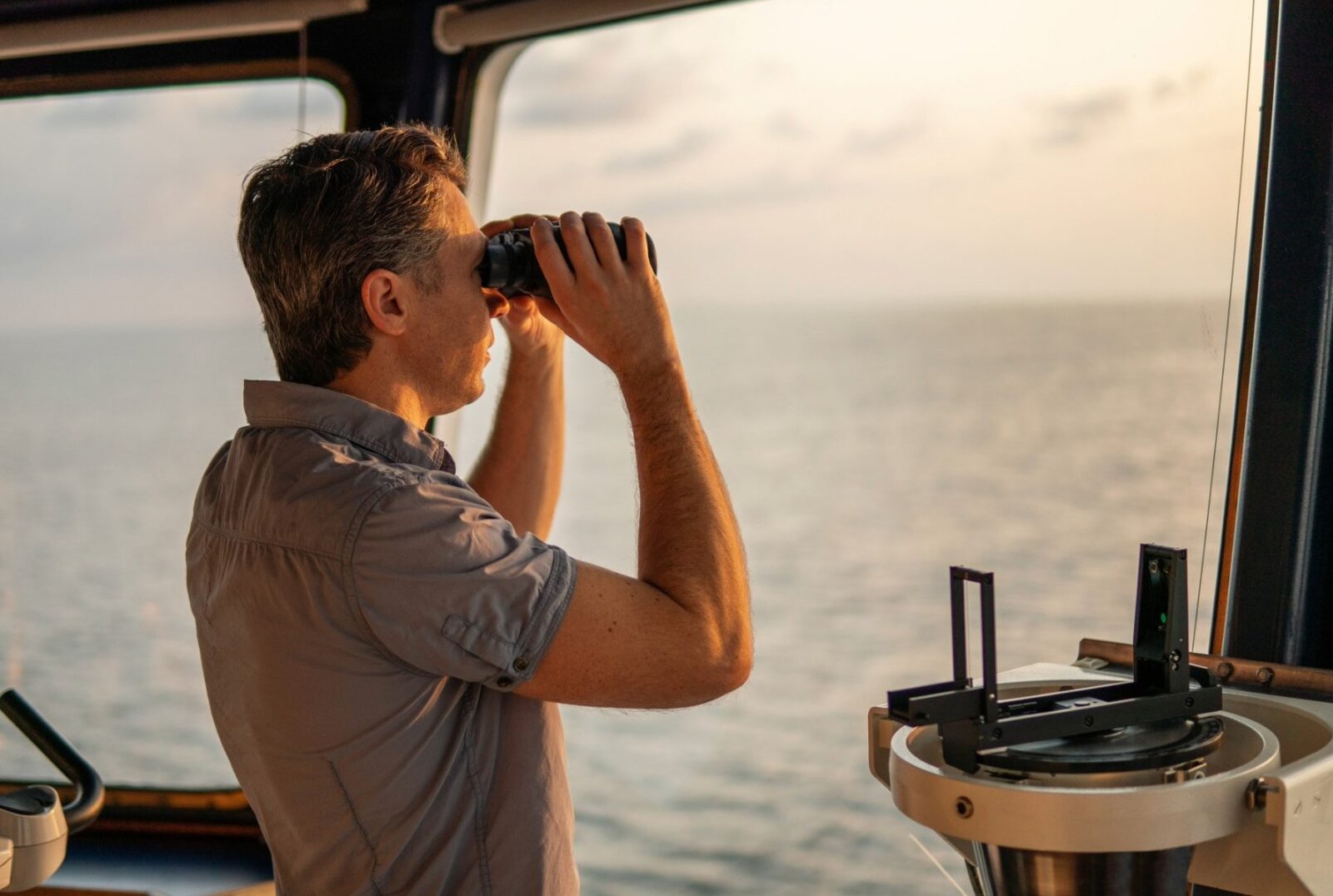 Navigational officer lookout on navigation watch looking through binoculars.,Marine industry.,COLREG collision regulations